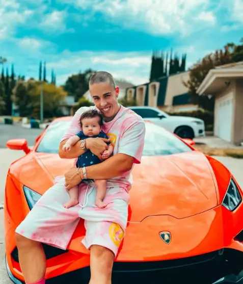 Ken posing in front of his Lamborghini with his baby boy